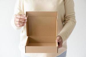 kvinna händer bärande brun öppning kartong låda. begrepp av använder sig av återvinna papper låda. foto