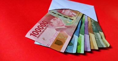 indonesiska rupiah i en vit kuvert isolerat på röd bakgrund foto