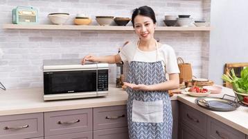 ung asiatisk kvinna framställning till laga mat i de kök foto