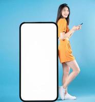 full längd Foto av ung asiatisk kvinna använder sig av smartphone på blå bakgrund