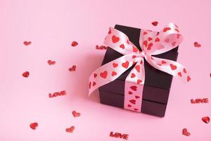 närvarande gåva låda med rosett på rosa bakgrund. valentines dag gåva och hjärtan foto