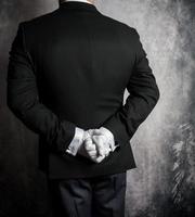 porträtt av butler eller concierge i mörk kostym och vit handskar stående på uppmärksamhet med händer Bakom hans tillbaka. elegant service och professionell artighet. foto