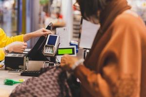 kvinna kund betalande via kreditera kort använder sig av nfc teknologi i handla köpcenter. foto