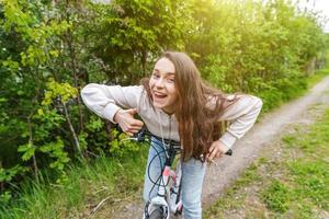 ung kvinna ridning cykel i sommar stad parkera utomhus. aktiva människor. hipster flicka koppla av och ryttare cykel foto