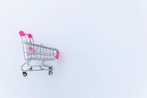 liten stormarknad livsmedelsbutik push-vagn för shopping leksak med hjul isolerad på vit bakgrund. rea köpa köpcentret marknaden butik konsument koncept. kopieringsutrymme. foto