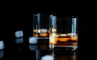 elegant enkel glas av lyx whisky mot svart bakgrund. skinande whisky glas isolerat bakgrund, studio skott. copyspace. stark alkohol dryck. foto