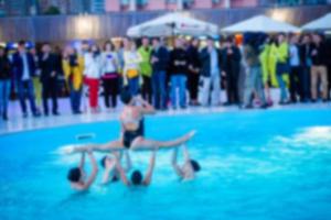 suddig bild av aqua kondition med grupp av senior människor utövar i simning utomhus- slå samman foto