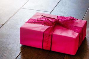 gåva med rosa band, hjärta och band på trä- bakgrund foto