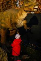 liten flicka i en parkera av dinosaurier foto