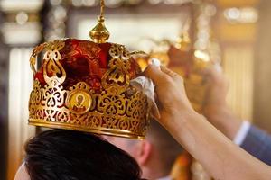 bröllop ceremoni brud och brudgum i de ortodox kyrka. vittnen håll kronor över de huvuden av de nygifta foto