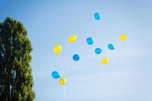 blå och gul ballonger i de stad festival på blå himmel bakgrund foto