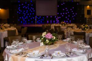 skön tabell miljö med porslin och blommor för en fest, bröllop reception eller Övrig festlig händelse. glas och bestick för sörjt händelse middag. foto