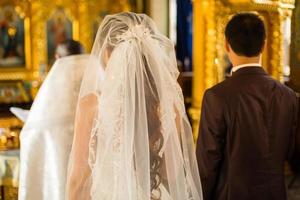 underbar brud och eleganta brudgum innehav ljus på officiell bröllop ceremoni i gammal kyrka. traditionell ögonblick foto