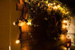 trä- naturlig krans dekorerad med Glödlampa lampor på bröllop ceremoni. dämpa ljus foto