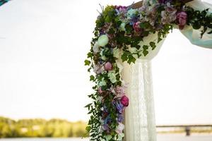 båge för de bröllop ceremoni, dekorerad med trasa och blommor foto