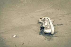 gyllene sko strandade spolades upp sopor föroreningar på stranden Brasilien. foto