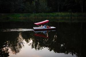 människor är segling på en katamaran på de sjö på de bakgrund på solnedgång. foto