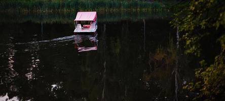 människor är segling på en katamaran på de sjö på de bakgrund på solnedgång. foto