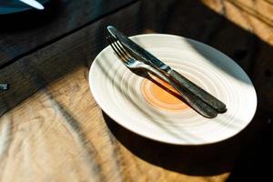tömma tallrik med kniv och gaffel på årgång trä- tabell foto