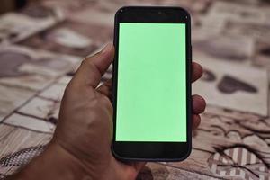 händer innehav smart telefon, grön skärm foto