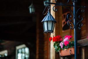 gammal rostig lykta på en trä- hus och blommor foto