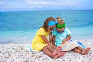 liten förtjusande flickor med stor Karta på tropisk strand semester foto