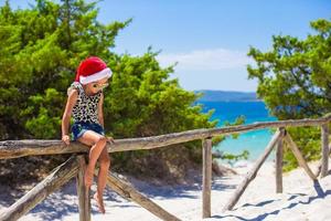 förtjusande liten flicka i jul hatt under sommar strand semester foto