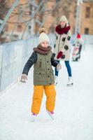 förtjusande liten flicka skridskoåkning på de is rink utomhus foto