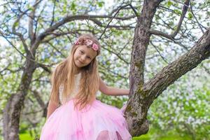 porträtt av liten skön flicka i blomstrande äpple trädgård foto