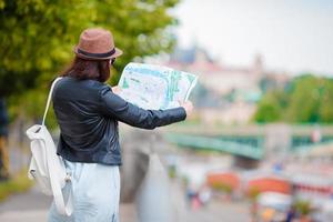 skön kvinna med turistiska stadskarta i de stad. Lycklig flicka njut av europeisk semester Semester i Europa. foto