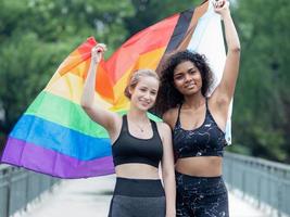 två lesbisk människor vänskap med regnbåge stolthet flagga. glad Gay person har roligt tillsammans med jämlikhet respekt till kärlek och frihet livsstil. mångfald av ung homosexuell par, lgbtq rättigheter. foto