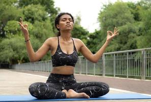 skön kvinna praktiserande yoga utomhus- i de lugn natur parkera. kvinna person fritid aktivitet är meditation, avslappning mindfulness övning för friska livsstil och fredlig andlighet. foto