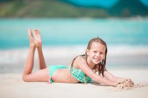 förtjusande liten flicka på strand har en massa av roligt i grund vatten foto