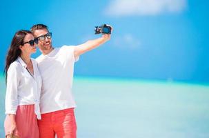 Lycklig par tar en selfie Foto på vit strand. två vuxna njuter deras semester på tropisk exotisk strand