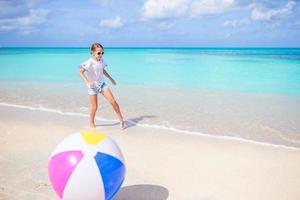 förtjusande liten flicka spelar med boll på strand, barn sommar sport utomhus foto