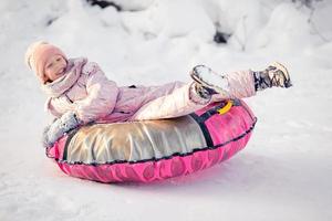 förtjusande liten Lycklig flicka sledding i vinter- snöig dag. foto