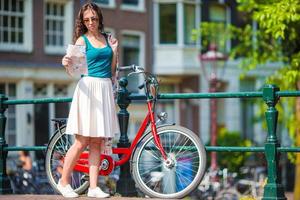 Lycklig ung kvinna med stad Karta och Cyklar i europeisk stad foto