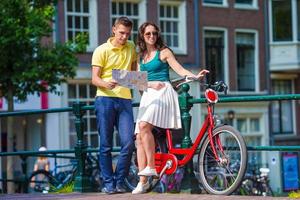 ung turister par ser på Karta med Cyklar i europeisk stad foto