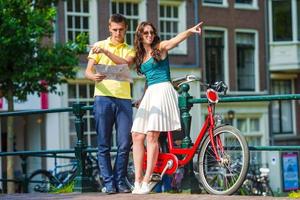 ung turister par ser på Karta med Cyklar i europeisk stad foto
