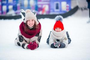 liten förtjusande flicka med henne mamma skridskoåkning på isbana foto