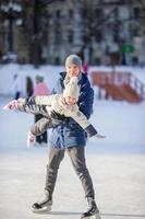 familj av far och unge har roligt på skridskoåkning rink utomhus foto