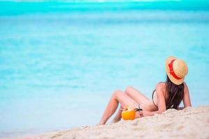 ung kvinna med kokos i bikini njuter de Sol solbad förbi perfekt turkos hav. foto