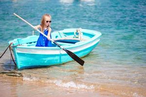 liten flicka i blå båt i de hav bukt i grekland foto