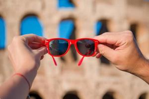 närbild solglasögon i händer i främre av colosseum i rom, Italien foto