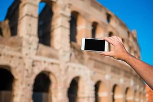 närbild cell telefon i främre av colosseum i rom, Italien foto