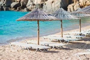 strand trä- stolar och paraplyer för semester på strand i grekland foto