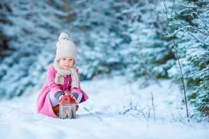 förtjusande liten flicka bär värma täcka utomhus på jul dag värms upp kall händer förbi ficklampa foto