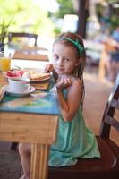 förtjusande liten flicka har frukost på tillflykt restaurang foto