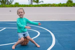 liten flicka ha roligt med basketboll på de utomhus- domstol foto