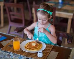 förtjusande liten flicka har frukost på tillflykt restaurang foto